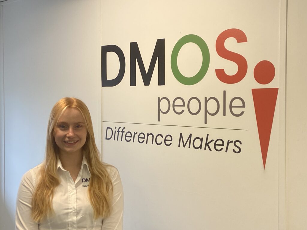 Charlotte Clarke in front of the DMOS People sign